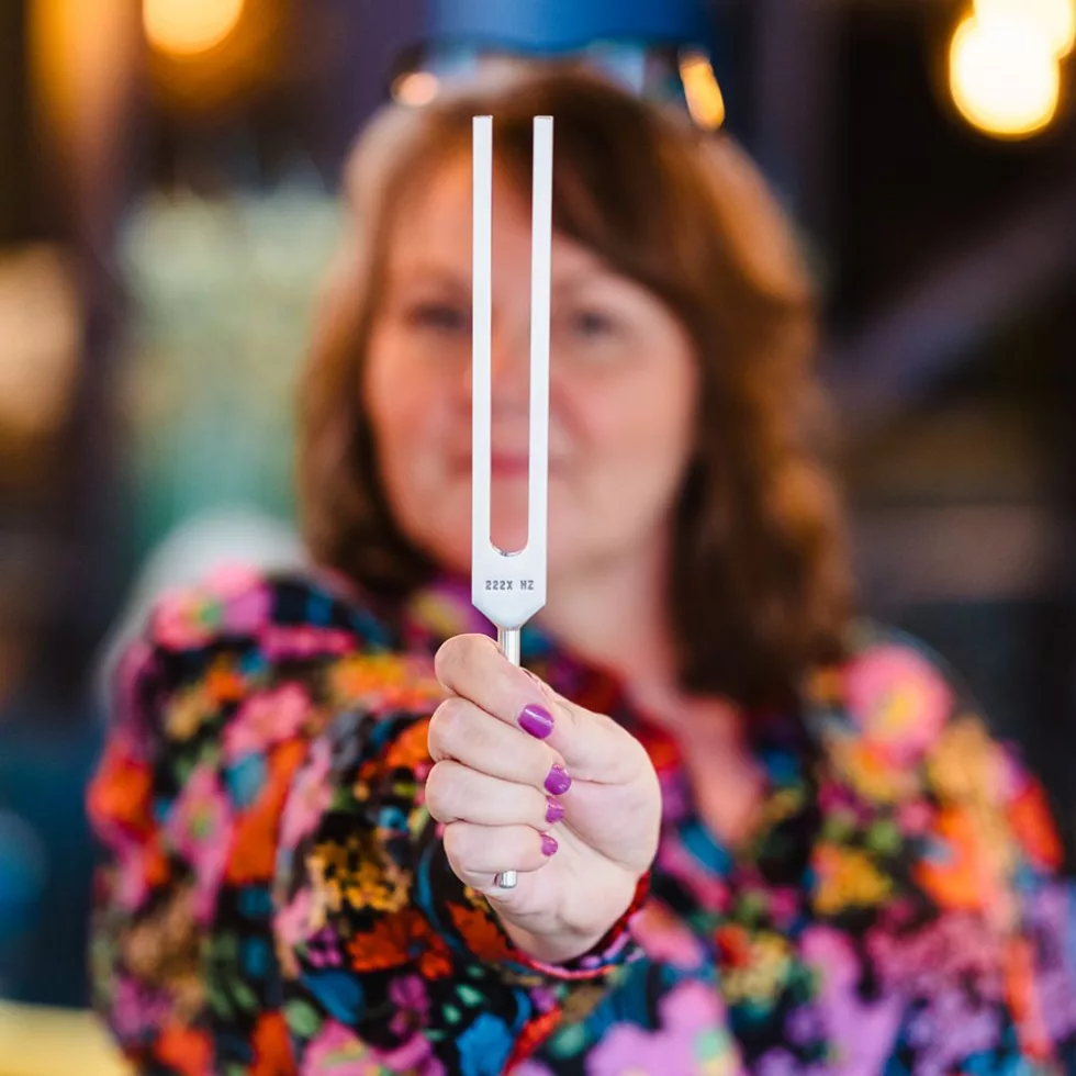 Kellie Rose holding up a tuning fork, the tool used in Biofield Tuning sessions